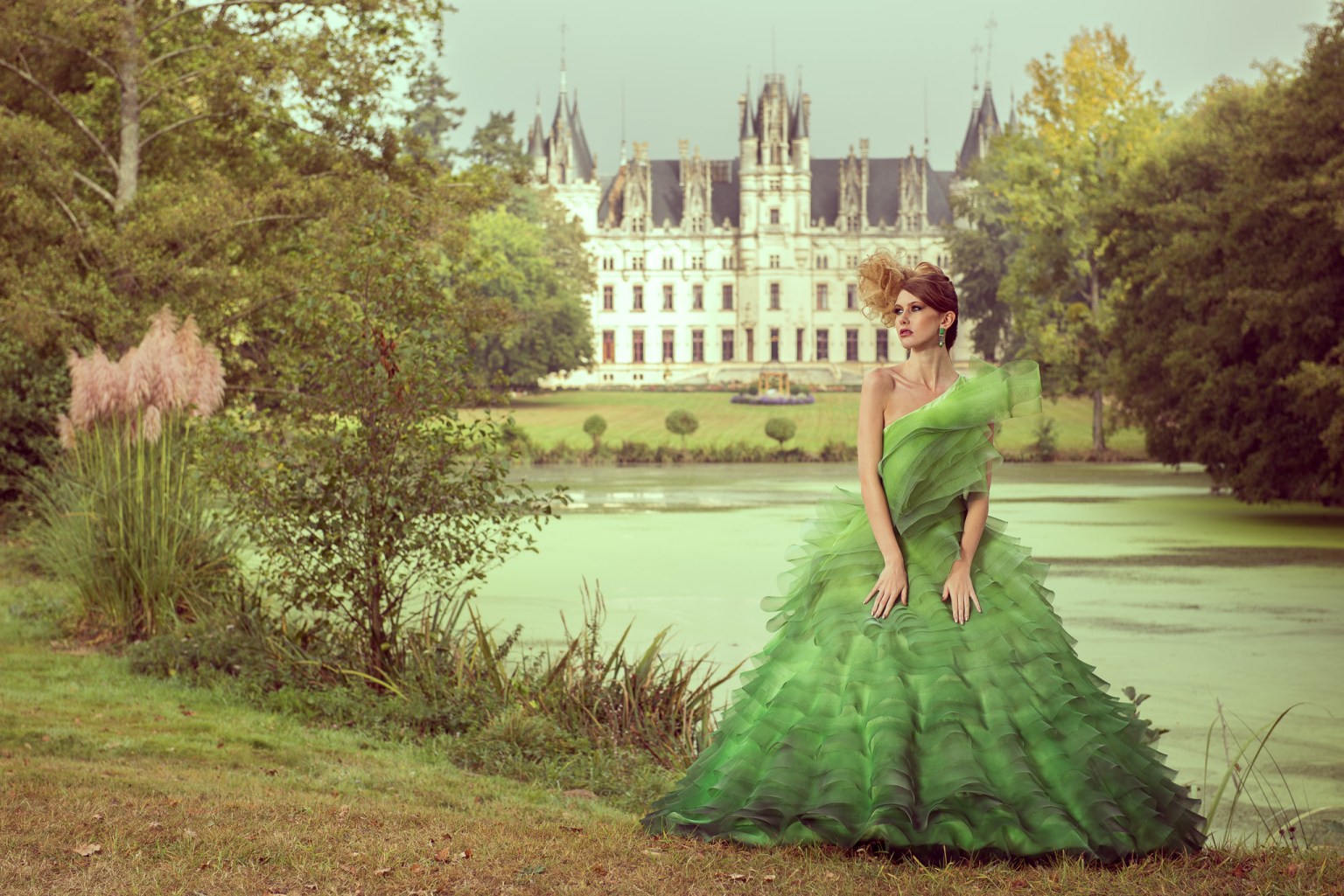 woman in green designer dress posing in front of a huge French chateaux