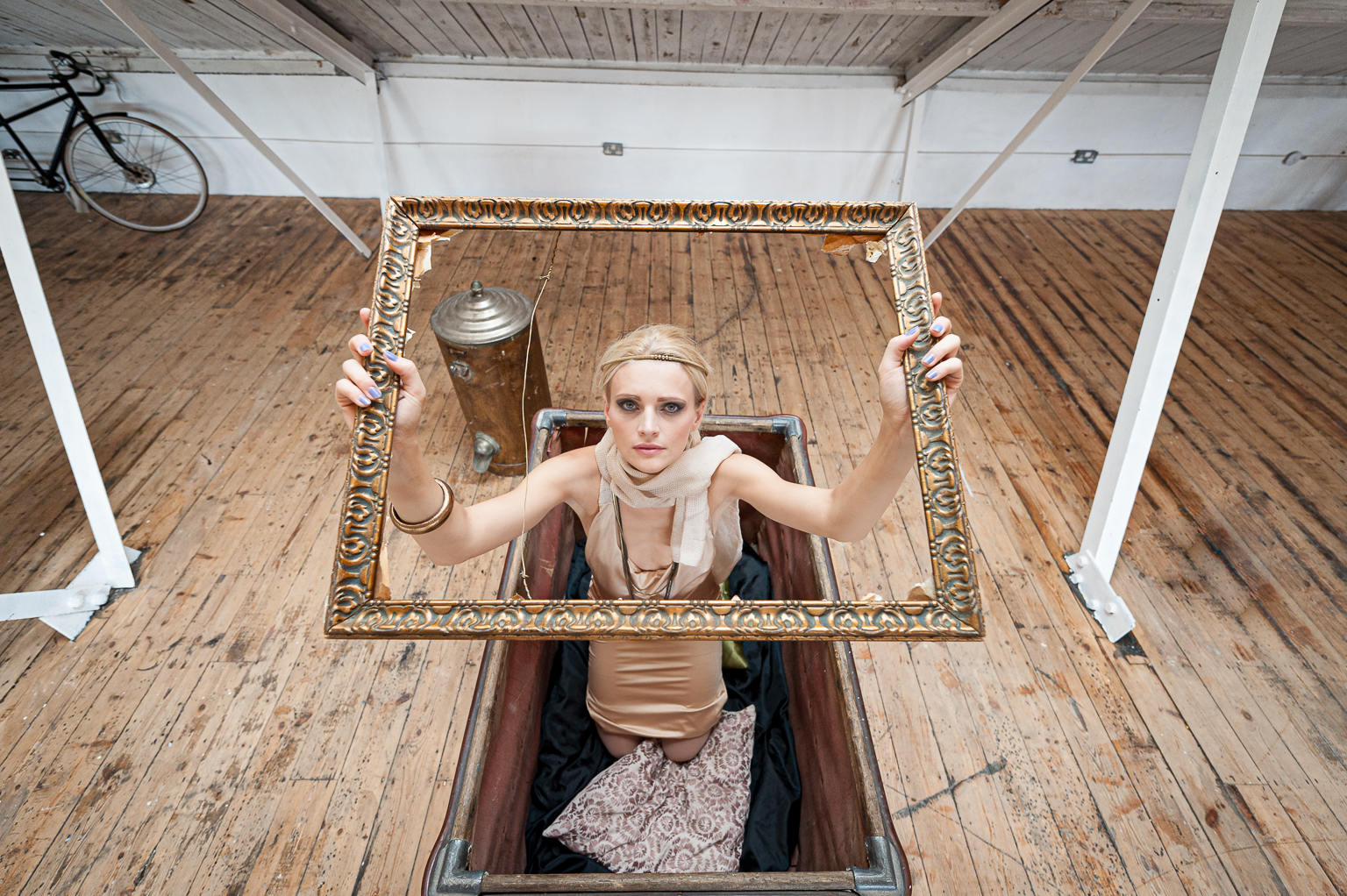 conceptual fashion with model in a box holding up an old empty picture frame and looking through it. Hung in Rankin's fashion art gallery. Taken by Ian Mears