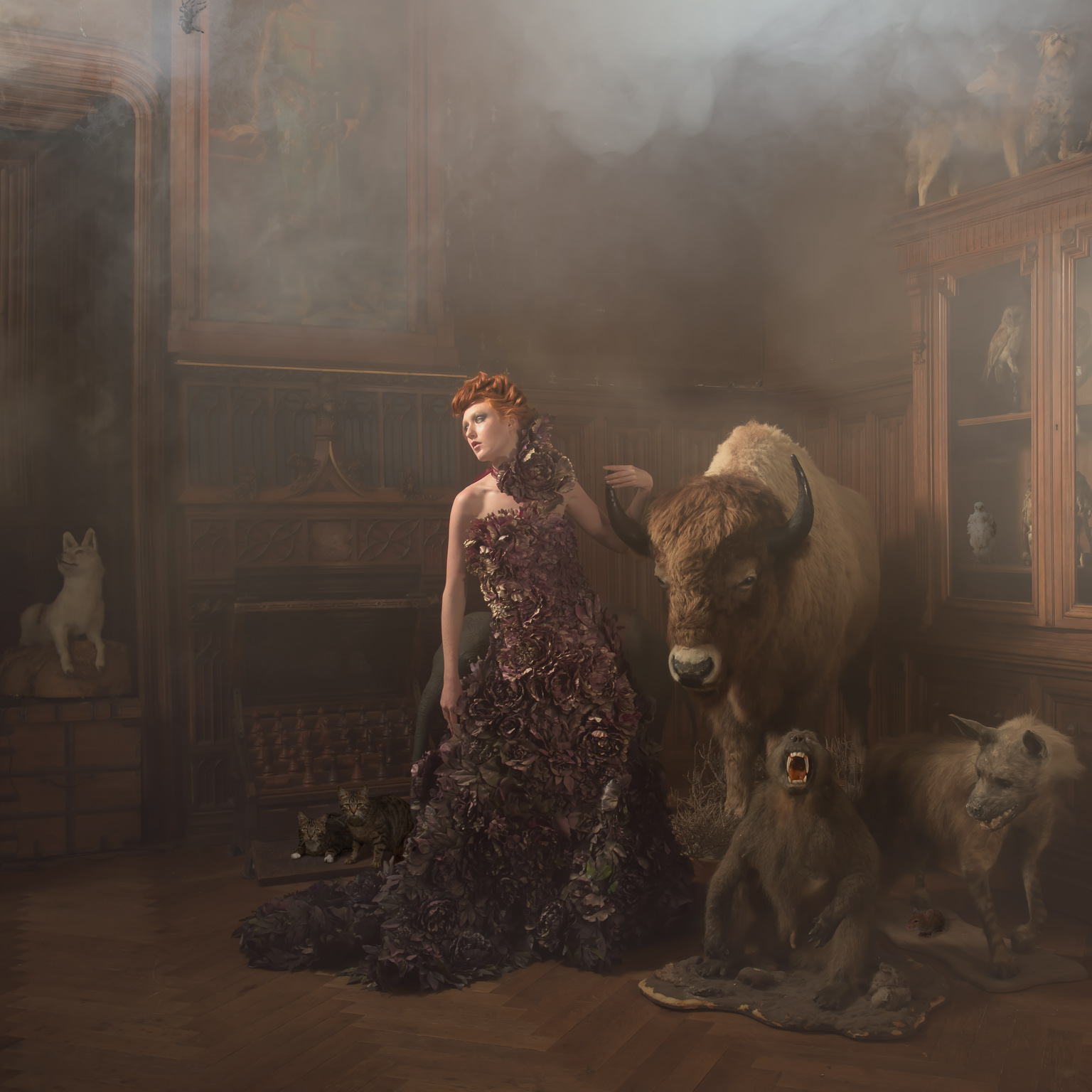 A model posing in chateau de challain, France, surrounded by stuffed animals and some photoshopped live animals with some smoke floating in the air